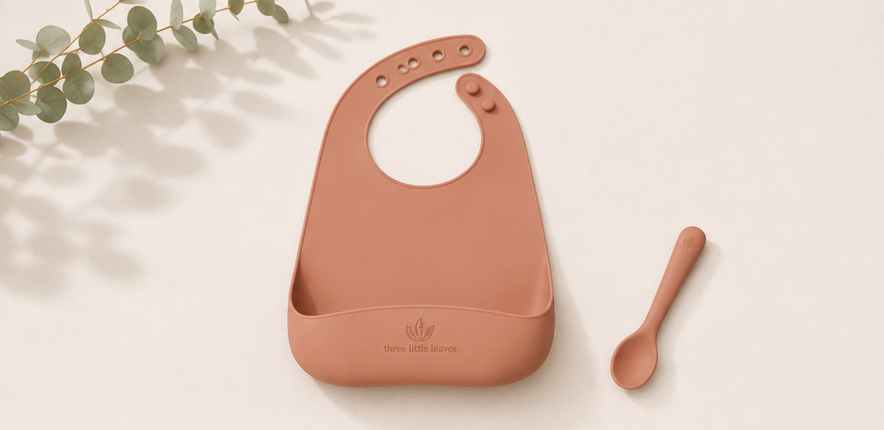 Silicon baby bib and spoon set in relaxed rust colour. Suitable for weening babies.